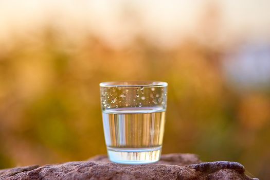 The glass of cool fresh water on nature background