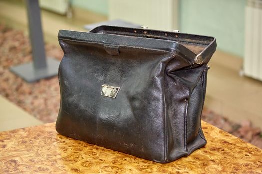 Rich businessman opening a leather briefcase filled with dollar packs, top view, unrecognizable person