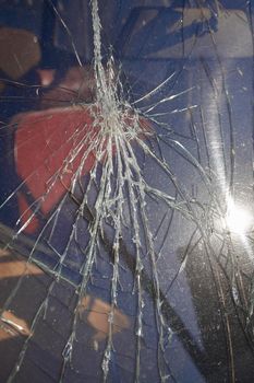 Cracks and glass shards radiate from the point of impact in a window that has been hit by an object