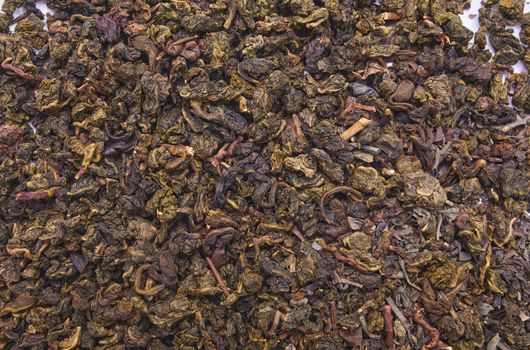 Milk oolong tea on a white background and close-up.Dry oolong tea leaves as a background. Fermented Chinese tea shot from above.