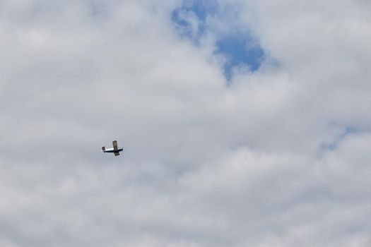 Small plane or airplane flying over blue sky with white clouds