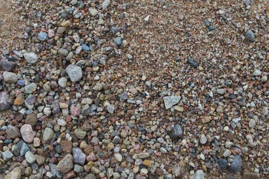 Gravel, pebbles and sand closeup.Detail surface textures with a small pebble rock on the muddy ground.