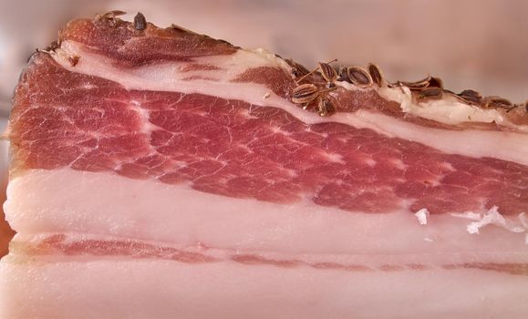 Raw pork brisket with caraway seeds, salt and pepperlying. Salty pork brisket. Closeup