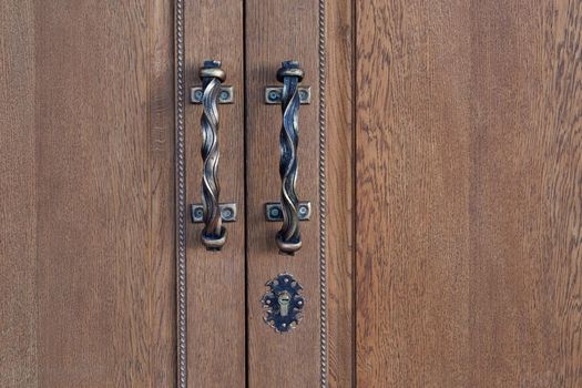 Detail of antique, wooden doors with an ornate lock and pens