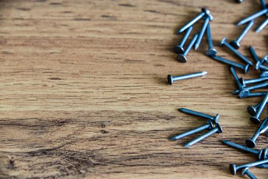 Heap of thin metal nails close up on wooden surface with copy space.