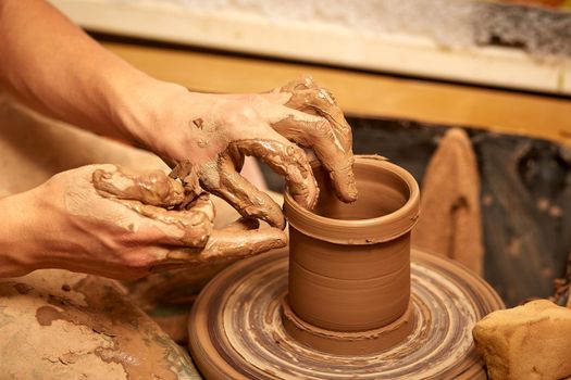 Creating a jar or vase of white clay close-up. Man hands making clay jug macro. The sculptor in the workshop makes a jug out of earthenware closeup.