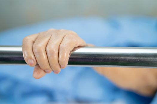 Asian senior or elderly old woman patient lie down handle the rail bed with hope on a bed in the hospital.