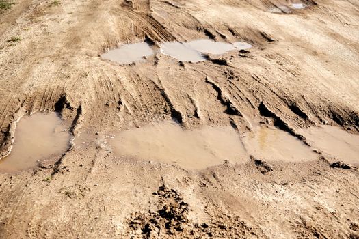 many puddles on a dirt sandy road