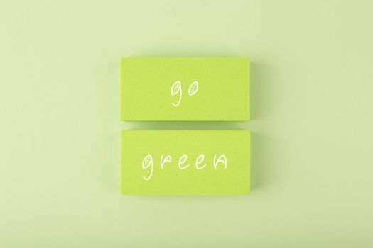 Modern minimal composition with go green inscription against light pastel green background. Concept of go green, recycle, reduce, reuse and eco friendly lifestyle