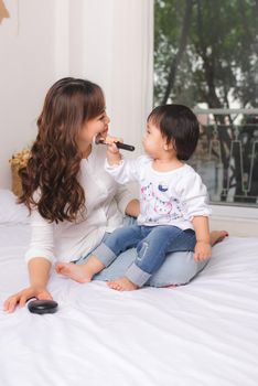 Lovely princess is applying the make up on her skin with special brush as she wants to look like her adult mother