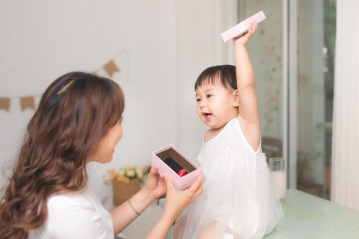 Happy family, beautiful young mother with her adorable little daughter open gift box