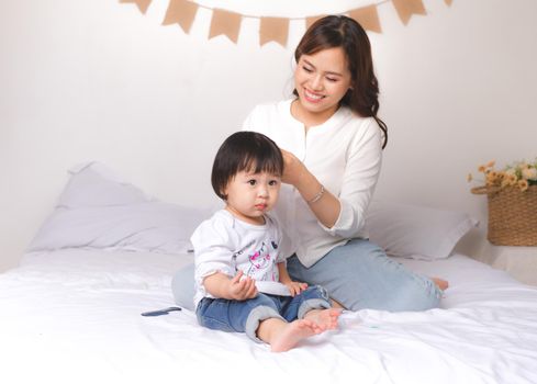 Happy family, beautiful young mother brushing hair of her adorable little daughter