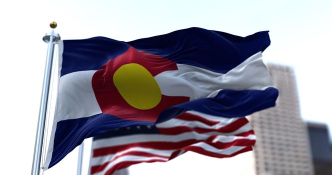 the flag of the US state of Colorado waving in the wind with the American stars and stripes flag blurred in the background. Colorado was it admitted in 1876 as the 38th of the Union. Independence and unity