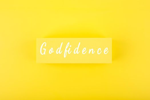 Godfidence single word against bright yellow background. Modern biblical creative religious concept of faith