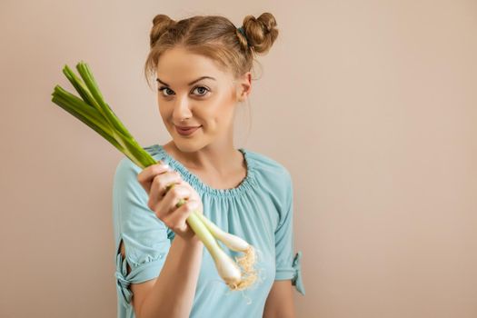 Portrait of cute woman holding young onion.Toned image.