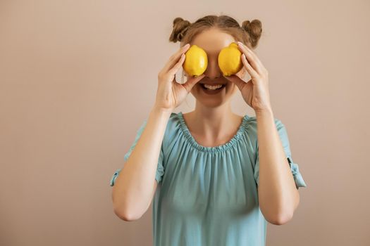 Cute blonde woman is covering her eyes with lemon.Toned image.