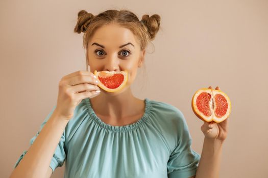 Portrait of cute playful woman holding slices of grapefruit.Toned image.