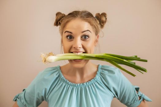 Portrait of cute playful woman eating young onion.Toned image.