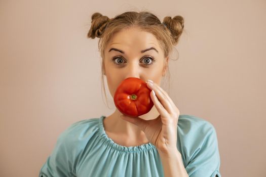 Portrait of cute playful woman holding tomato.Toned image.