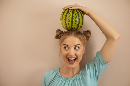 Cute playful woman holding  watermelon on her head.Toned image.