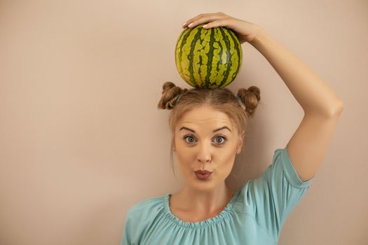 Cute playful woman holding  watermelon on her head.Toned image.