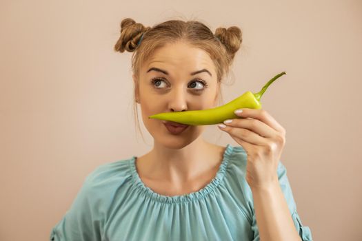 Cute playful woman holding green pepper.Toned image.