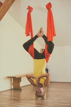 Woman doing aerial yoga in the fitness studio.Image is intentionally toned.