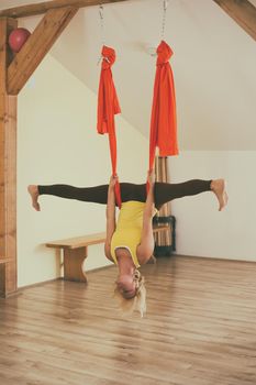 Woman doing aerial yoga in the fitness studio.Image is intentionally toned.