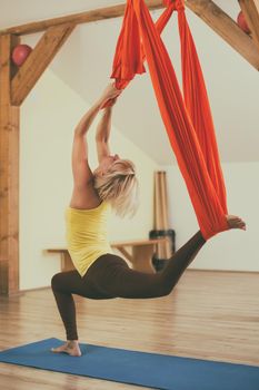 Woman doing aerial yoga in the fitness studio.Image is intentionally toned.