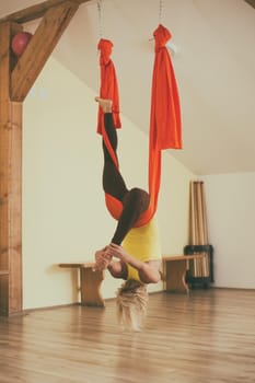 Woman doing aerial yoga in the fitness studio.Image is intentionally toned.