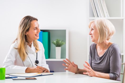 Female doctor and senior woman patient talking in doctor's office
