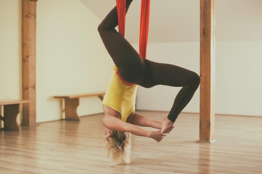Woman doing aerial yoga in the fitness studio.Image is intentionally toned.
