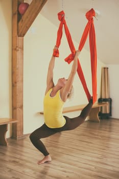 Woman doing aerial yoga in the fitness studio.Image is intentionally toned.