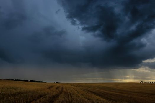 Dark storm clouds in an agricultural field in autumn. An impending storm, hurricane or thunderstorm. Bad extrime weather.