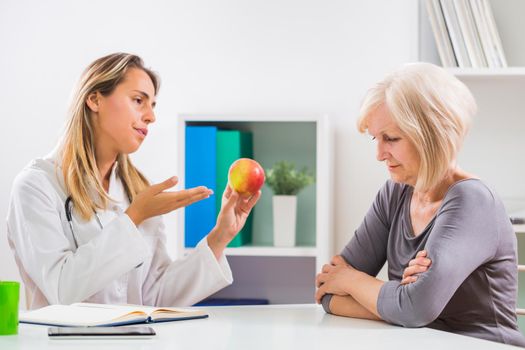 Senior woman patient refusing to eat fruit which is good for her health.