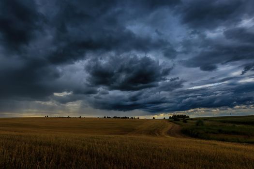 Dark storm clouds in an agricultural field in autumn. An impending storm, hurricane or thunderstorm. Bad extrime weather.