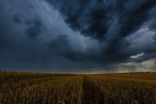 Dark storm clouds in an agricultural field in autumn. An impending storm, hurricane or thunderstorm. Bad extrime weather.