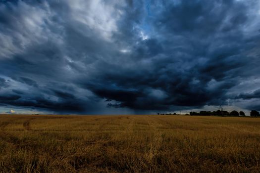 Dark storm clouds in an agricultural field in autumn. An impending storm, hurricane or thunderstorm. Bad extrime weather.
