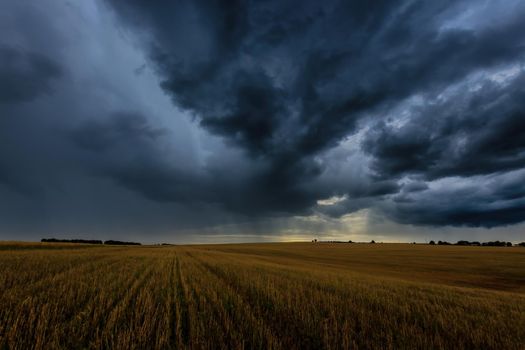 Dark storm clouds in an agricultural field in autumn. An impending storm, hurricane or thunderstorm. Bad extrime weather.