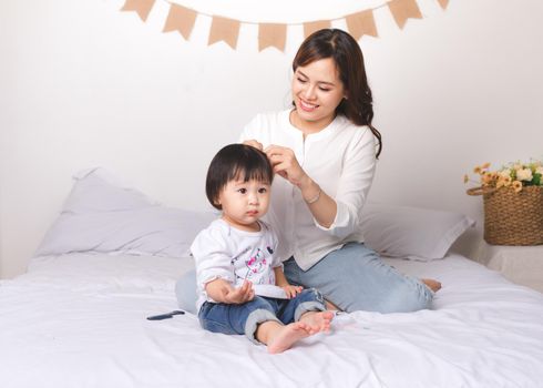 Happy loving family. Mom and child girl are having fun on the bed.