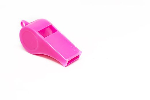A pink plastic whistle isolated on a white background. Tool for sport and training. Warning and shrill sound