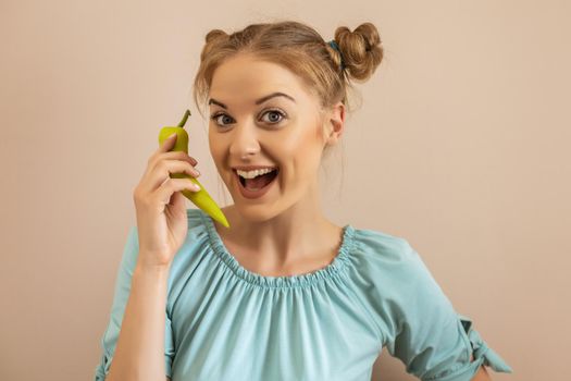 Cute playful woman holding green pepper.Toned image.