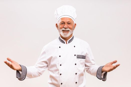 Portrait of senior chef gesturing  on gray background.