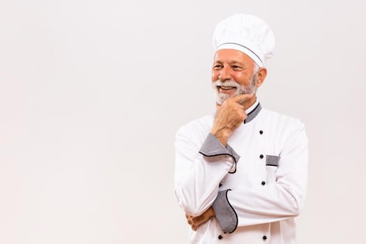 Portrait of senior chef thinking  on gray background.