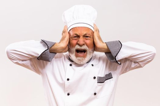Portrait of  senior chef in panic on gray background.
