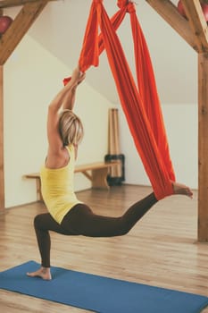 Woman doing aerial yoga in the fitness studio.Image is intentionally toned.