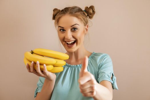 Portrait of cute happy woman holding bananas and showing thumb up.Toned image.