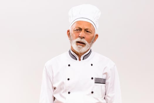 Image of exhausted senior chef on gray background.