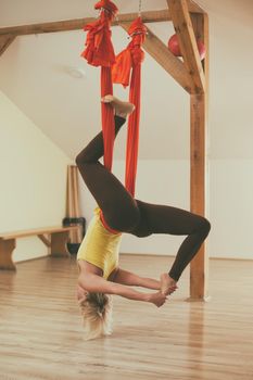 Woman doing aerial yoga in the fitness studio.Image is intentionally toned.