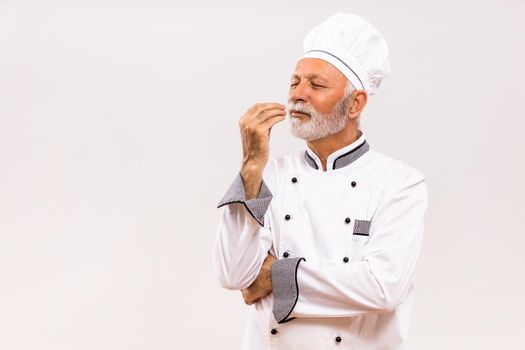 Portrait of senior chef showing delicious sign.